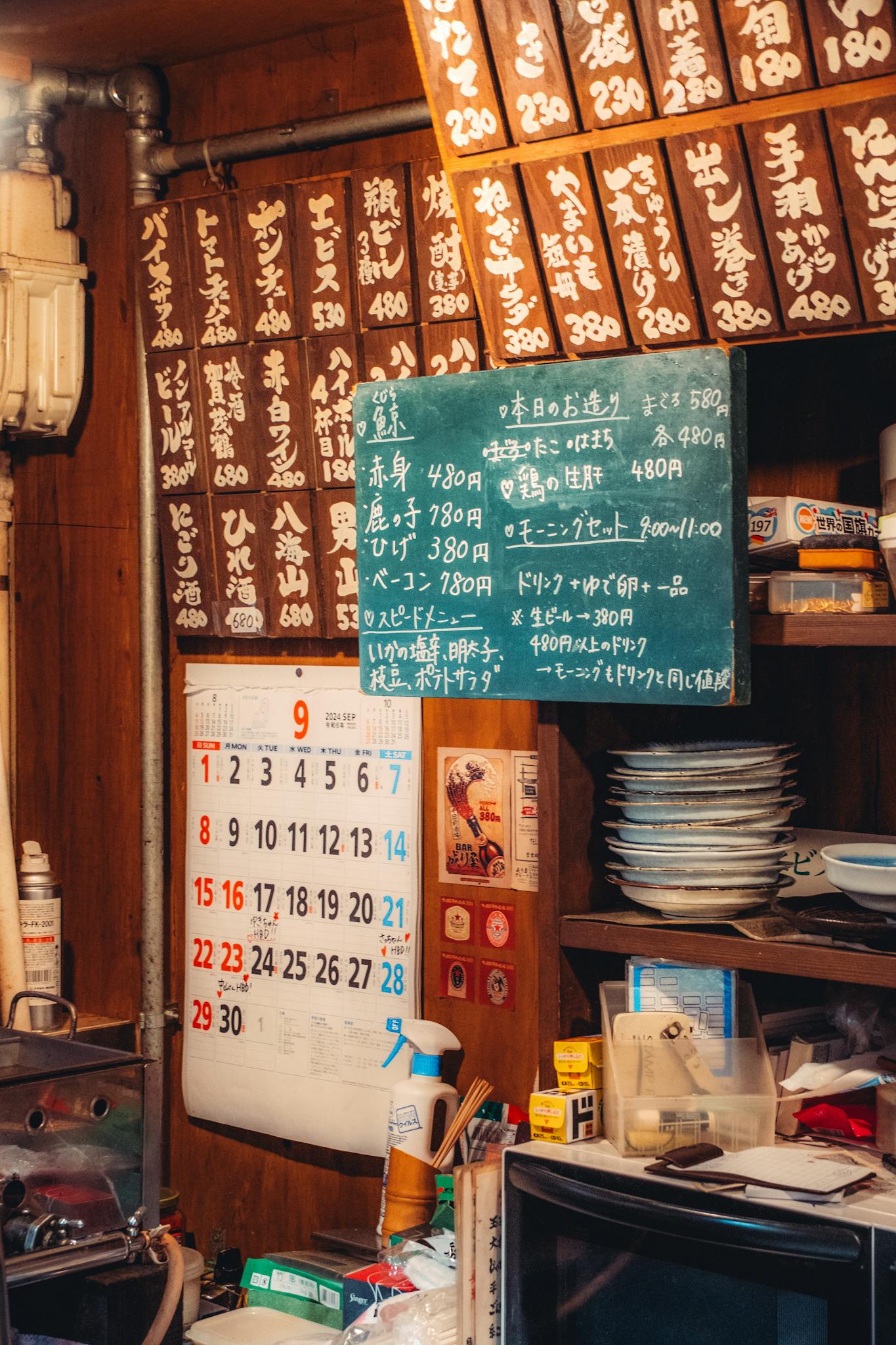 Warm interior of a Japanese kitchen displaying traditional menu boards and a calendar.